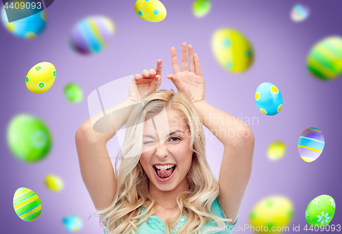 Image of happy woman making bunny ears over easter eggs