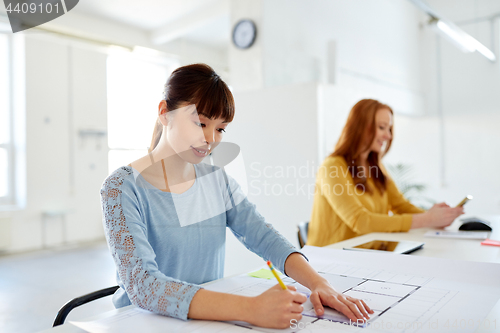 Image of female architect with blueprint working at office