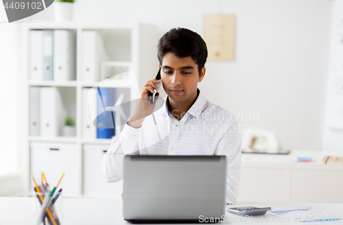 Image of businessman calling on smartphone at office