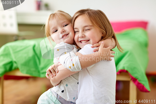 Image of happy little girls or sisters hugging at home