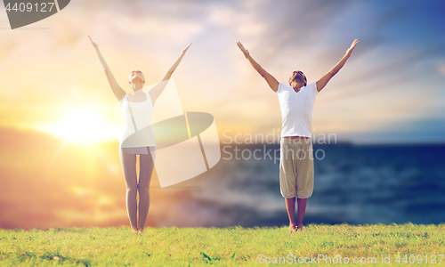 Image of couple making yoga exercises outdoors