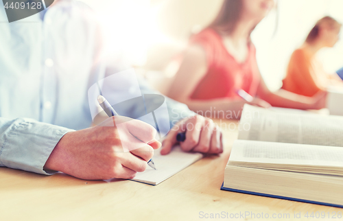 Image of close up of student writing to notebook at school