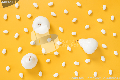 Image of White chocolate candies and painted fruits on yellow background