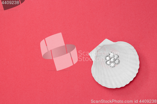 Image of Shiny gems in a seashell on pink background