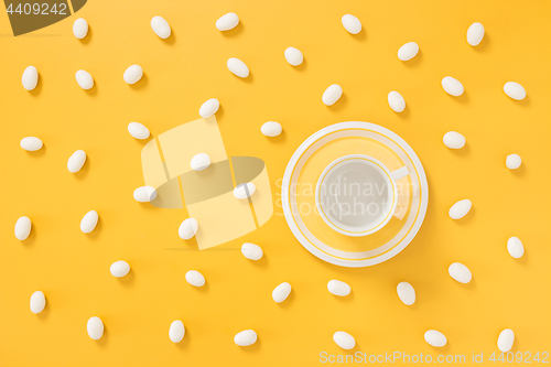 Image of White chocolate candies and teacup on yellow background