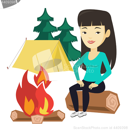 Image of Woman sitting on log near campfire in the camping.