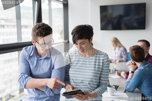 Image of Two Business People Working With Tablet in office