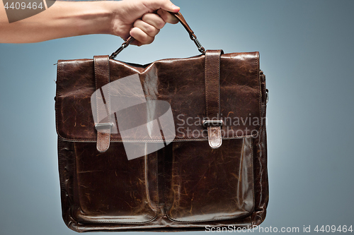 Image of A man holding a brown leather travel bag