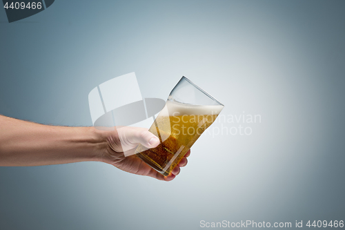 Image of Closeup of a male hand holding up a glass of beer