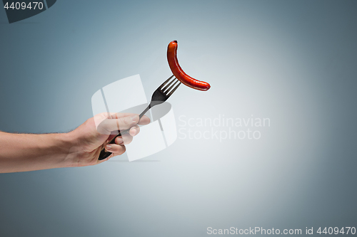 Image of sausage on a fork in his hand