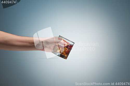 Image of Hand holding a glass of whiskey