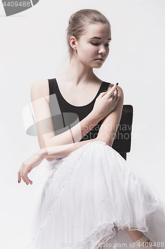 Image of The teen ballerina in white pack sitting on chair
