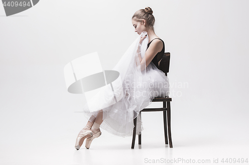 Image of The teen ballerina in white pack sitting on chair