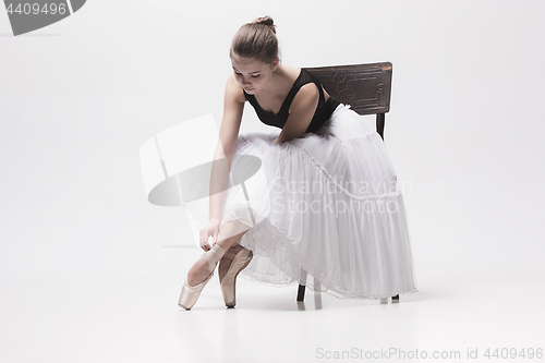 Image of The teen ballerina in white pack sitting on chair