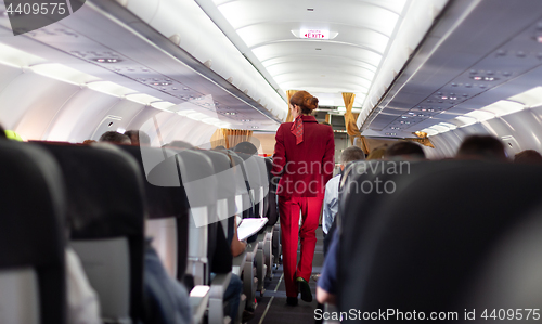 Image of Interior of commercial airplane with stewardess walking the aisle.