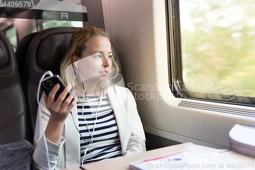 Image of Businesswoman communicating on mobile phone while traveling by train.