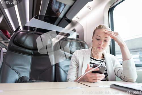 Image of Businesswoman communicating on mobile phone while traveling by train.