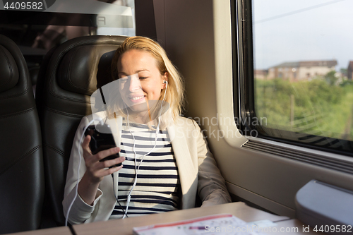 Image of Businesswoman communicating on mobile phone while traveling by train.