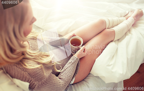 Image of close up of woman with tea cup in bed