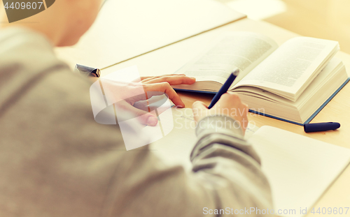 Image of close up of student writing to notebook at school