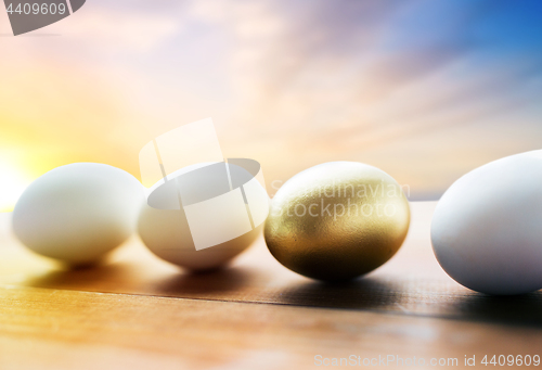 Image of close up of golden and white easter eggs on wood