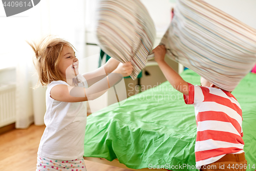 Image of kids playing and fighting by pillows at home