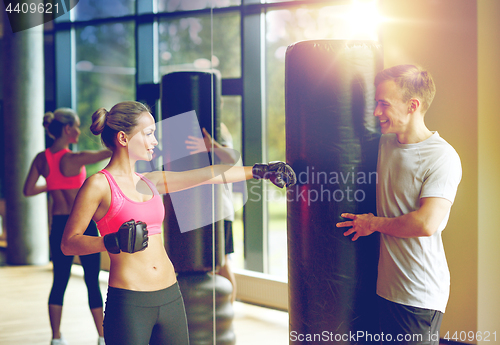 Image of smiling woman with personal trainer boxing in gym