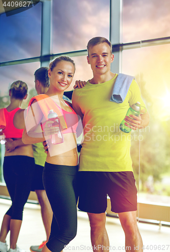 Image of smiling couple with water bottles in gym