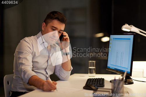 Image of businessman calling on sartphone at night office