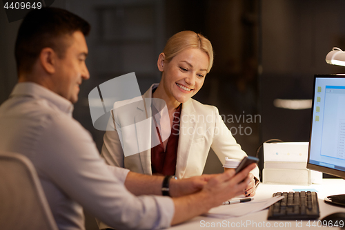 Image of business people with smartphone at night office