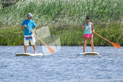 Image of Man and woman stand up paddleboarding