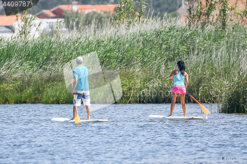 Image of Man and woman stand up paddleboarding