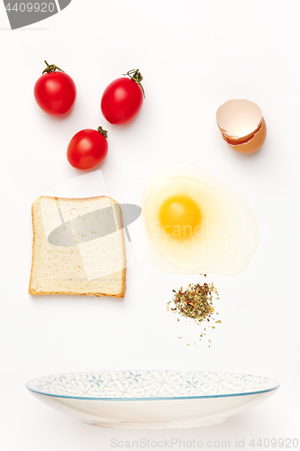 Image of The falling ingredients of fried egg. Healthy breakfast ingredients.