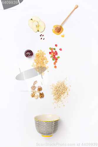 Image of Falling granola with falling blueberries and honey flows from dipper.