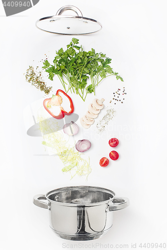 Image of Assorted fresh vegetables falling into a bowl, on white background