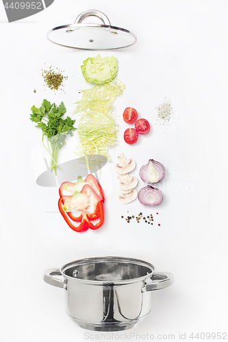 Image of Assorted fresh vegetables falling into a bowl, on white background