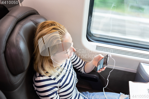 Image of Woman communicating on mobile phone while traveling by train.