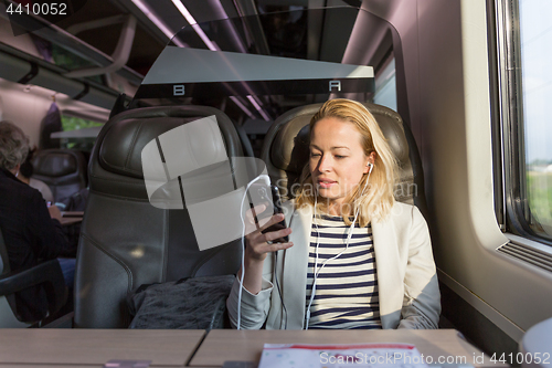 Image of Businesswoman communicating on mobile phone while traveling by train.