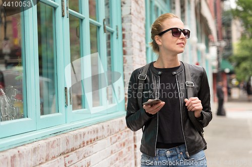 Image of Female traveler using smart phone app guite on city break weekend trip to New York.