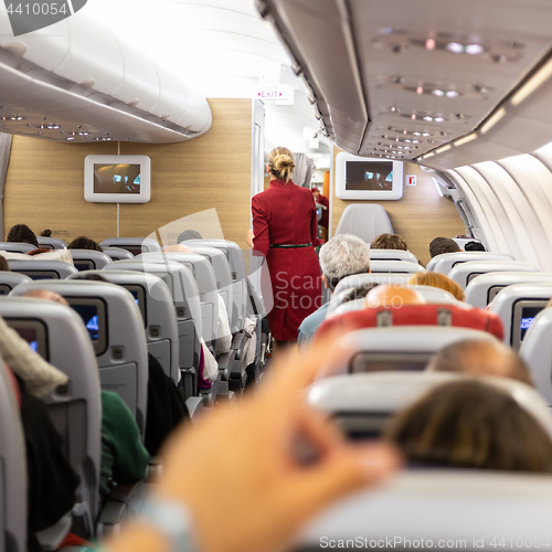 Image of Interior of commercial airplane with stewardess walking the aisle.