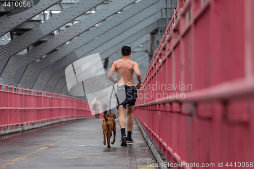 Image of Unrecognizable topless recreational runner and a dog at Williamsburg bridgein New York CIty, USA.