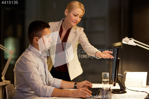 Image of business team with computer working late at office
