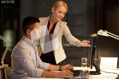 Image of business team with computer working late at office