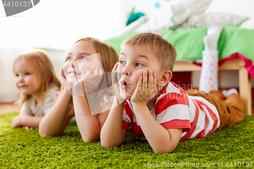 Image of happy little kids lying on floor or carpet