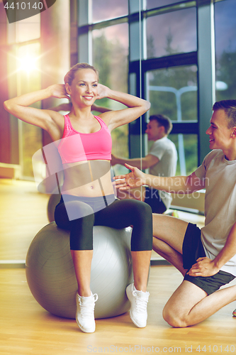 Image of smiling man and woman with exercise ball in gym