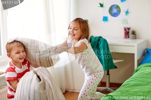 Image of kids playing and fighting by pillows at home