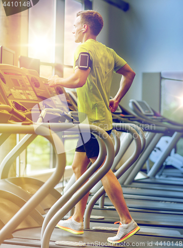 Image of man with smartphone exercising on treadmill in gym