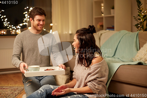 Image of happy couple with food on tray at home