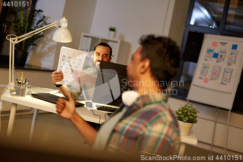 Image of creative man showing papers to colleague at office