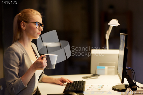 Image of businesswoman at night office drinking coffee